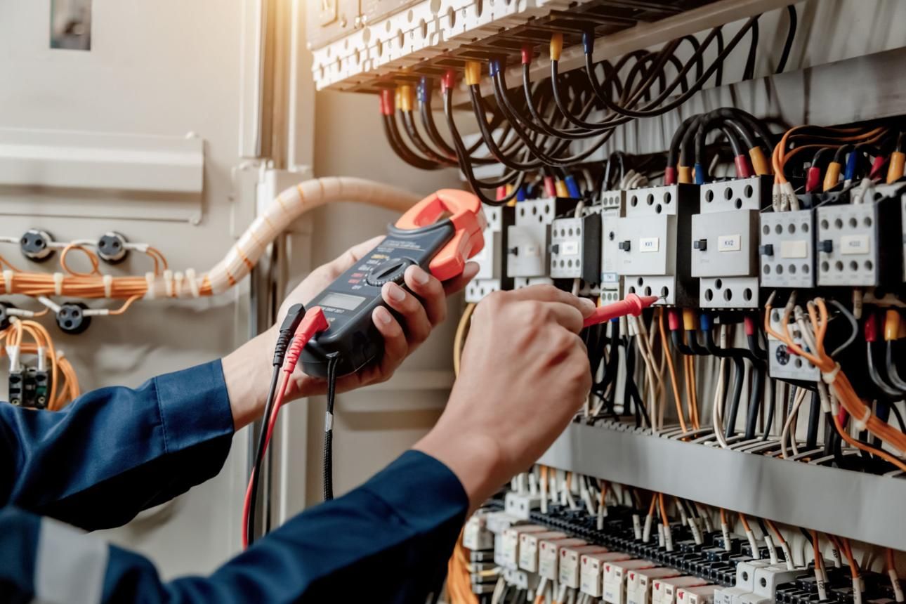 Electrician testing a switchboard with a clamp meter